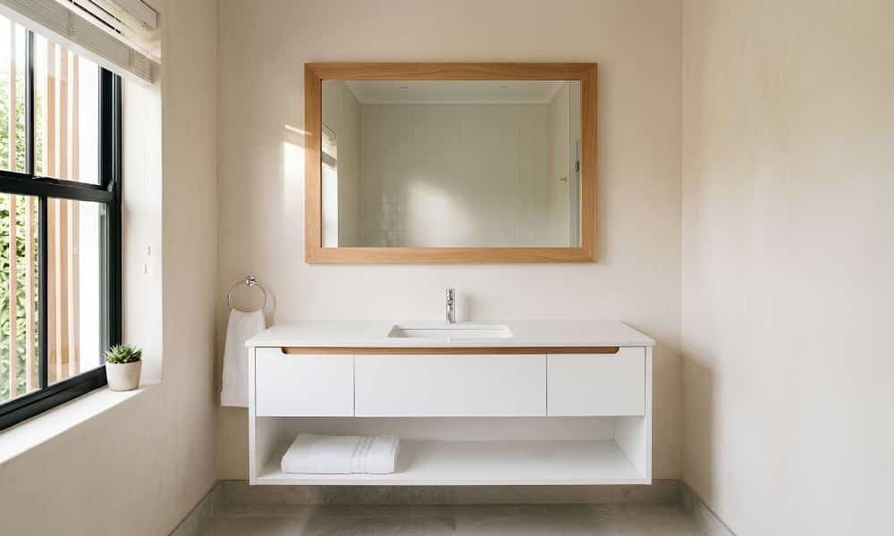 DIY bathroom mirror with a wood frame above a white vanity